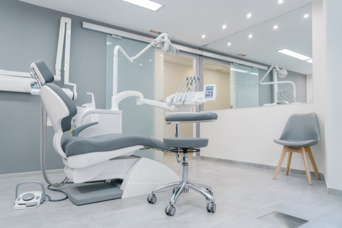 Gabinete dental moderno y luminoso, con sillón de tratamiento y paredes grises