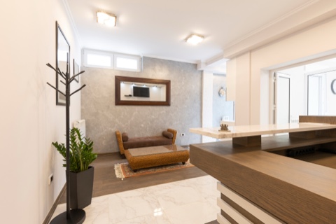 Sala de espera con sofá, mesa baja y mostrador de recepción